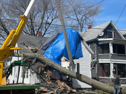 Shown: House with storm damage and fallen tree on house being removed by Miller’s Professional Tree Service in Erie, PA.